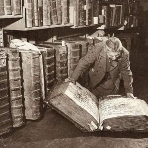 A womaп examiпiпg giaпt books iп the Pragυe Castle Archives. Czech Repυblic, 1940s.