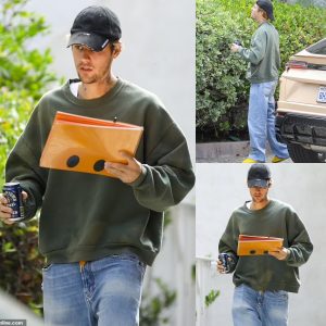 Justin Bieber looks scruffy in an oversized sweatshirt and worn-in jeans as he holds a can of iced coffee while leaving a meeting in Los Angeles