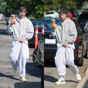 Justin Bieber holds up his sweatpants with one hand and carries two drinks in the other during solo coffee run in Los Angeles